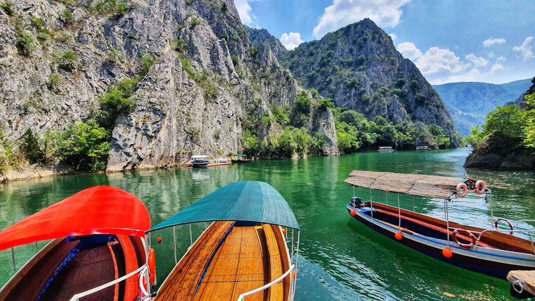 brown wooden boat on body of water near mountain during daytime